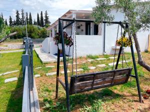 huśtawka w ogrodzie z domem w tle w obiekcie Gardy rooms w miejscowości Nea Kallikratia
