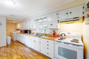 a kitchen with white cabinets and a white stove top oven at Birch Circle Beach House in Ogunquit