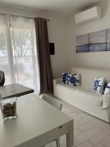sala de estar con sofá blanco y ventana en Isola Rossa Appartamenti Superior, en Isola Rossa