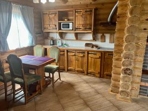 una cocina con armarios de madera, mesa y sillas en Боброва-Хата, en Svityazʼ