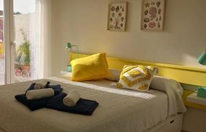 a bed with yellow and blue pillows on it at Alegre apto con piscina, a 300m de la playa. in Blanes +32 photos
