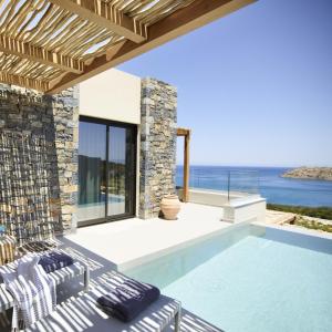 a villa with a swimming pool and the ocean at Cayo Exclusive Resort & Spa in Elounda