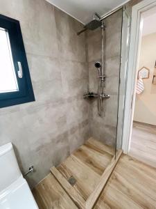 a shower with a glass door in a bathroom at Gardy rooms in Nea Kalikratia