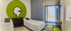 a small bedroom with two beds and a mirror at Hostal Baobab in El Puerto de Santa María
