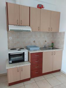 - une cuisine avec un évier, une cuisinière et des placards dans l'établissement Sunset Apartments, à Kanali