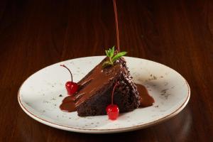 アレキパにあるHotel Santa Rosaのチェリーが添えられた皿の上のチョコレートケーキ