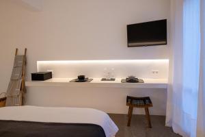 a room with a bed and a tv on a wall at SEAMENTO suites in Tinos