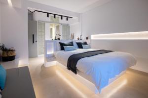 a white bedroom with a large white bed with blue pillows at SEAMENTO suites in Tinos