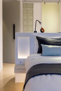 a bedroom with a white bed with a lamp on it at SEAMENTO suites in Tinos