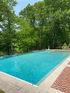une piscine bleue avec des arbres en arrière-plan dans l'établissement Rushmore Estate, à Woodbury