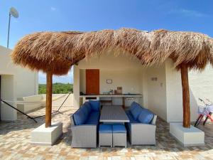 een patio met een tafel en stoelen en een rieten parasol bij Frida's Rooftop in Puerto Morelos