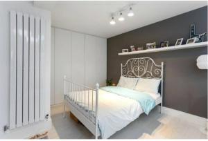 a bedroom with a white bed and a gray wall at Chetwynd Paradise in London