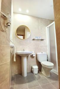 a bathroom with a sink and a toilet and a mirror at Hostal Noray in Sant Feliu de Guixols