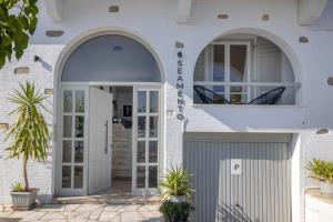 a white house with an arch doorway and a gate at SEAMENTO suites in Tinos