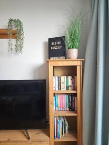 una estantería con libros y TV en Ferienwohnung Kleine Auszeit, en Sankt Englmar