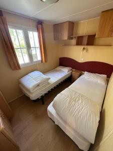 duas camas num pequeno quarto com duas janelas em mobil-home cosy, calme, therme, aquensis, casino em Bagnères-de-Bigorre