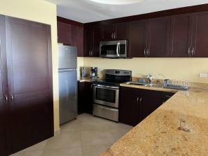 a kitchen with wooden cabinets and a stainless steel refrigerator at Calafia, Oceanview Condo Resort in Rosarito. in Rosarito