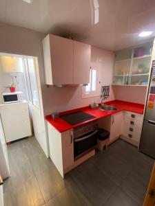 a small kitchen with red counter tops and white cabinets at Cozy apartment at a great location! in Hospitalet de Llobregat