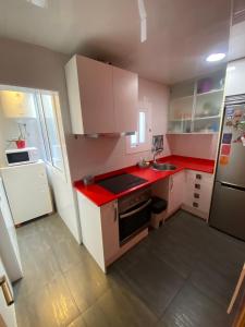 a small kitchen with red counters and white cabinets at Cozy apartment at a great location! in Hospitalet de Llobregat