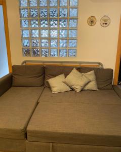 a couch with two pillows sitting under a window at Cozy apartment at a great location! in Hospitalet de Llobregat