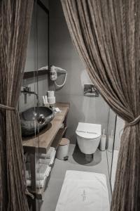 a bathroom with a toilet and a sink with curtains at King’s & Queen’s in Afitos