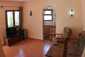 sala de estar con TV, mesa y sillas en El Cisne - holiday home with private swimming pool in Benissa, en Pedramala