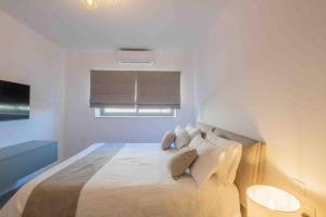 a white bedroom with a large bed with two pillows at Wanderlust 2 in Sliema