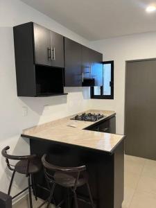 a kitchen with black cabinets and two bar stools at Departamento azinchite in Mazatlán