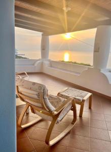a rocking chair on a porch with a view of the ocean at La Casuzza Dei Re in Malfa