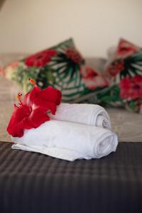 a white towel with a red flower on a bed at Maunga Roa Eco Lodge in Hanga Roa