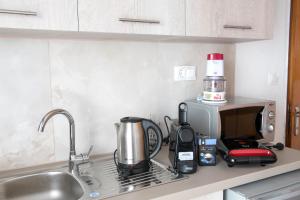 a kitchen counter with a coffee maker and a microwave at Gold Sand Apartments in Paralia Katerinis
