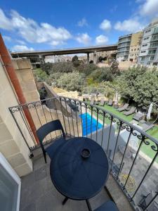 d'une table et de chaises sur un balcon avec piscine. dans l'établissement The Valley Room 6 with parking on premises, à San Ġiljan