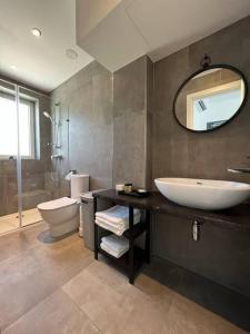 een badkamer met een wastafel, een toilet en een spiegel bij The Valley Room 6 with parking on premises in St Julian's