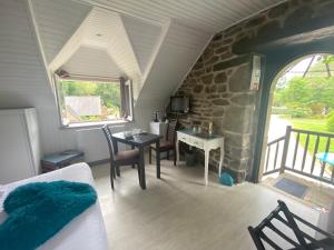 a room with a table and chairs and a stone wall at Les Moulins Du Duc ÉCOLODGE in Moëlan-sur-Mer