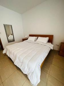 uma grande cama branca num quarto com um espelho em Tigne 3 Sliema one bedroom apartment em Sliema