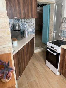 eine kleine Küche mit einem Herd und einer Mikrowelle in der Unterkunft Serenity 2 in Qormi
