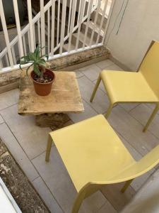 Qormi的住宿－Serenity 2，门廊上两把黄色椅子和一盆盆植物
