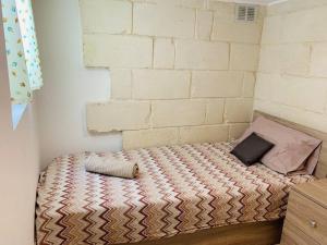 a small bed in a room with a brick wall at Serenity in Qormi