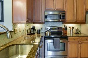 a kitchen with stainless steel appliances and wooden cabinets at Mount Pleasant Condo with Pool and Bikes Near Beach! in Charleston