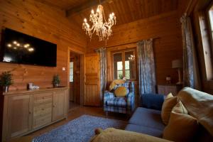 a living room with a couch and a chandelier at tranquil log cabin in Shepton Mallet