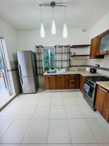 a kitchen with a stainless steel refrigerator and wooden cabinets at Lovely 3 bedroom in Siggiewi in Siġġiewi