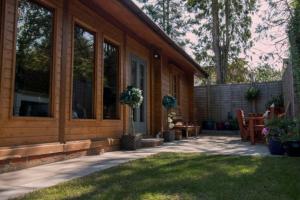 tranquil log cabin في شيبتون ماليت: شرفة منزل مع كراسي وفناء