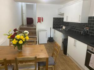 uma cozinha com uma mesa com um vaso de flores em Rusholme Rooms em Manchester