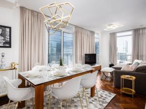 a dining room with a table and white chairs at Pristine Modern 2BR Condo Private BBQ and Balcony in Toronto