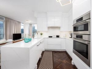 a white kitchen with white cabinets and a sink at Pristine Modern 2BR Condo Private BBQ and Balcony in Toronto