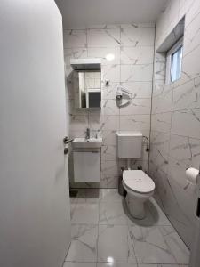 a white bathroom with a toilet and a sink at Villa Rosa Rooms in Punat