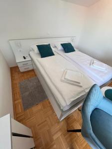 a bedroom with a large bed and a blue chair at Villa Rosa Rooms in Punat