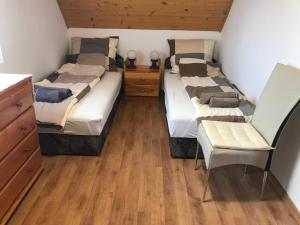 1 Schlafzimmer mit 2 Betten, einem Stuhl und Holzböden in der Unterkunft Sophie-Haus, Sophie-ház in Balatonmáriafürdő
