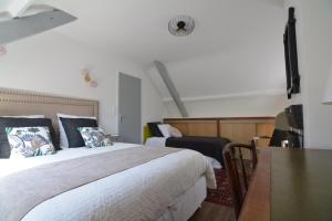 a bedroom with two beds and a table with a desk at Le Moulin De Branféré. in Le Guerno