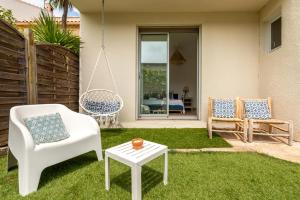 a yard with two chairs and a swing and a table at Villa Cavi Laurier in Le Grau-dʼAgde